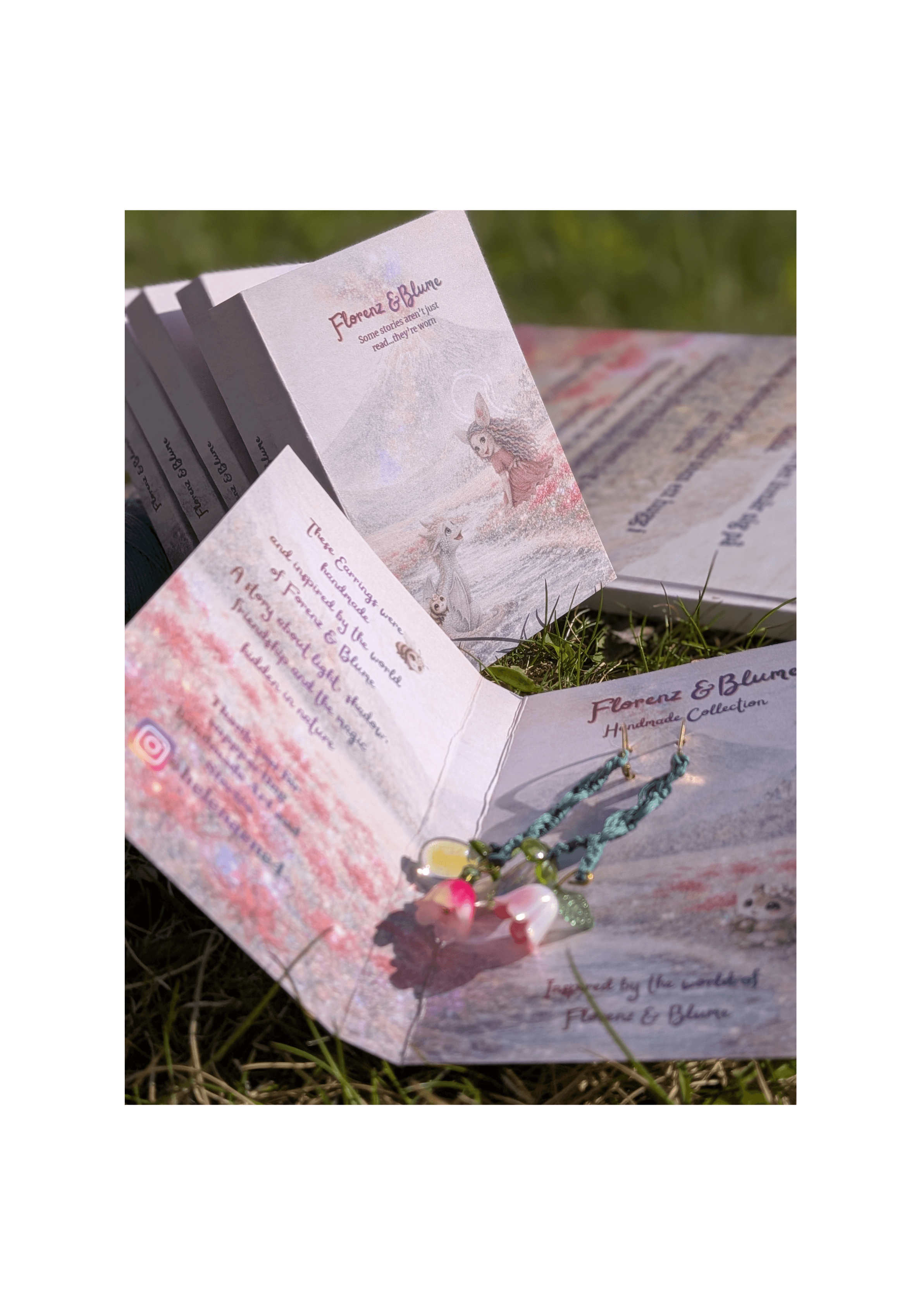 Handmade Florenz & Blume earrings on printed story cards in the grass