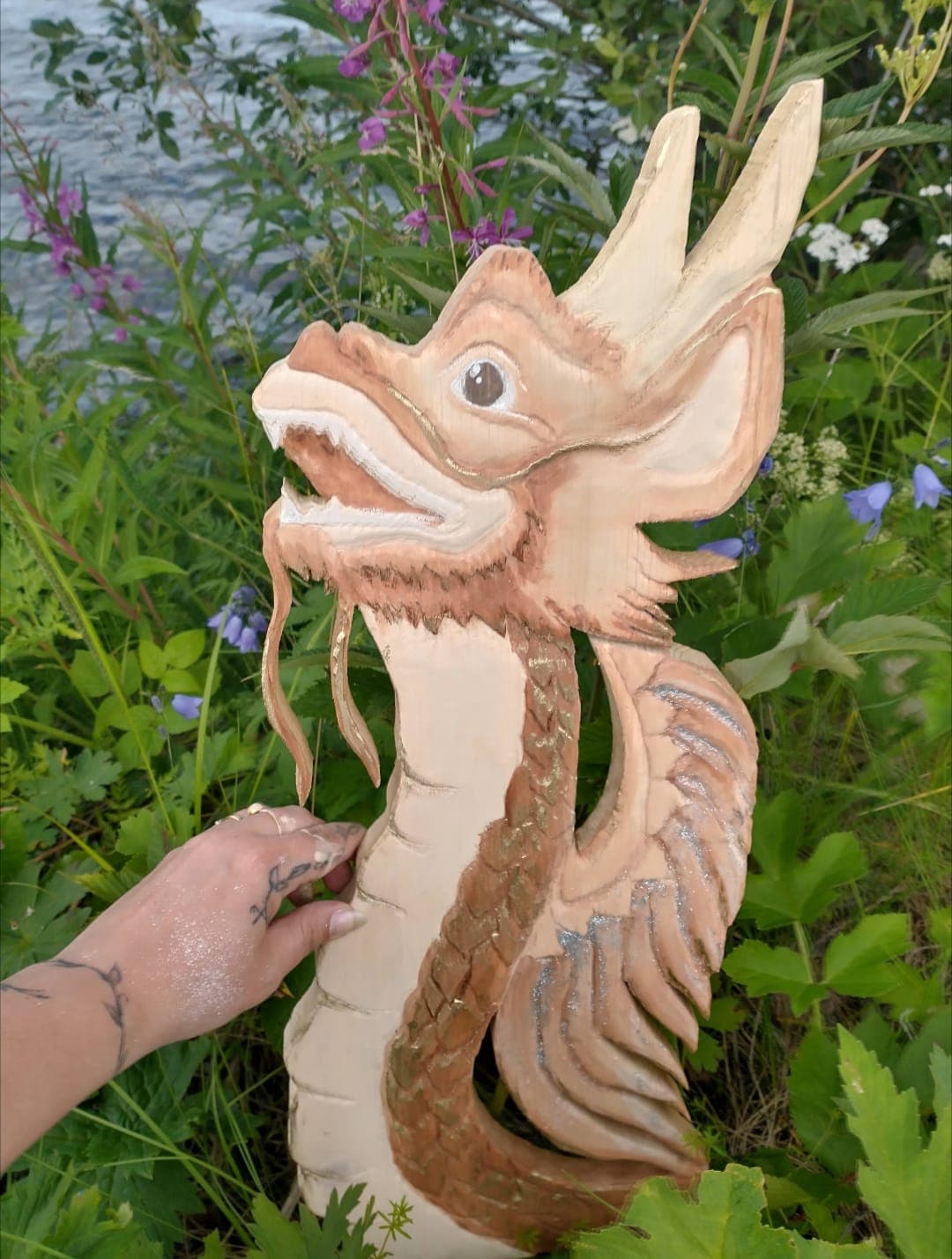 Hand-carved wooden Florenz dragon by a riverbank